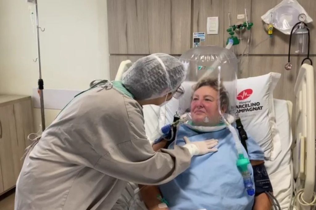 Elza Zawadzki utilizando o Helmet, cápsula respiratória que melhora a oxigenação dos pacientes