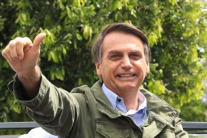 Bolsonaro sorrindo e fazendo sinal de positivo com a mão