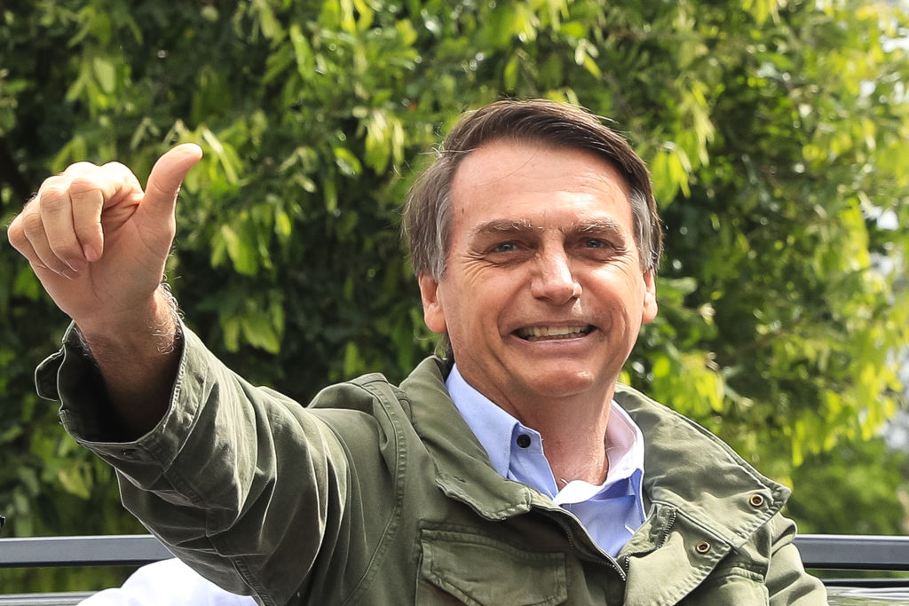 Bolsonaro sorrindo e fazendo sinal de positivo com a mão