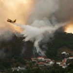 Avião anfíbio sobrevoa incêndio florestal em Portugal despejando água sobre a fumaça