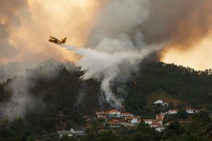 Avião anfíbio sobrevoa incêndio florestal em Portugal despejando água sobre a fumaça