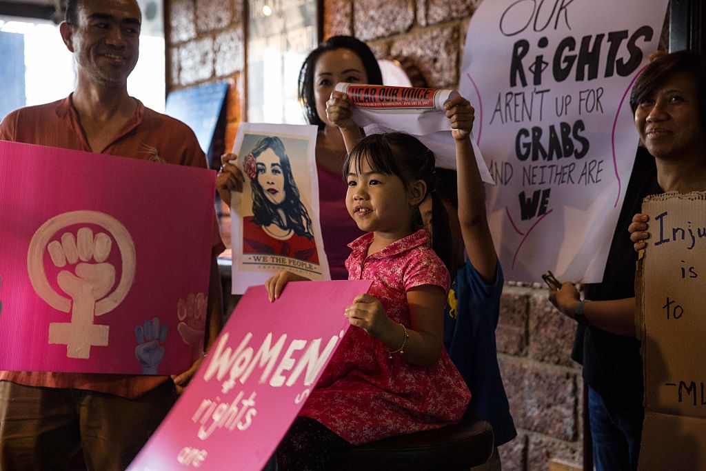 Garota tailandesa segura cartaz com reivindicações feministas em protesto.