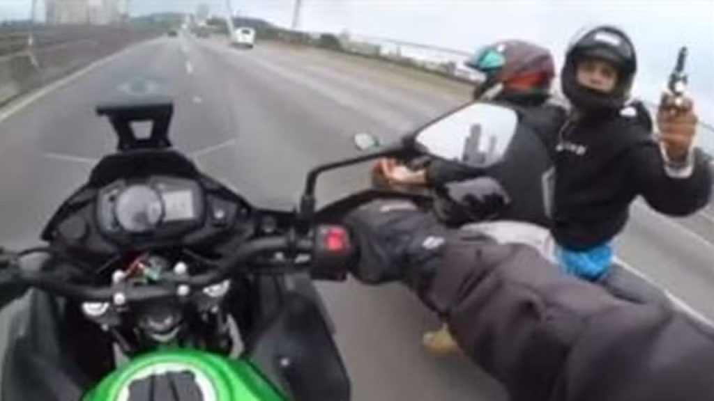 Uma câmera no capacete de um motociclista gravou o momento que um assaltante apontou a arma e ameaçou atirar se a vítima não parasse.